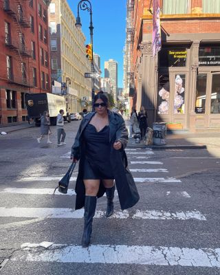 Woman wearing a minidress with tall boots and a long coat.