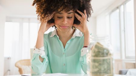 A frustrated woman with a jar of savings.