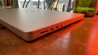 A 2023 14-inch MacBook Pro on a wooden counter, near a retro lamp.