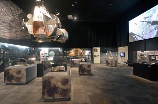 Apollo 11 artifacts on display under a mockup of an Apollo lunar module's ascent stage in Destination Moon at The Museum of Flight in Seattle.