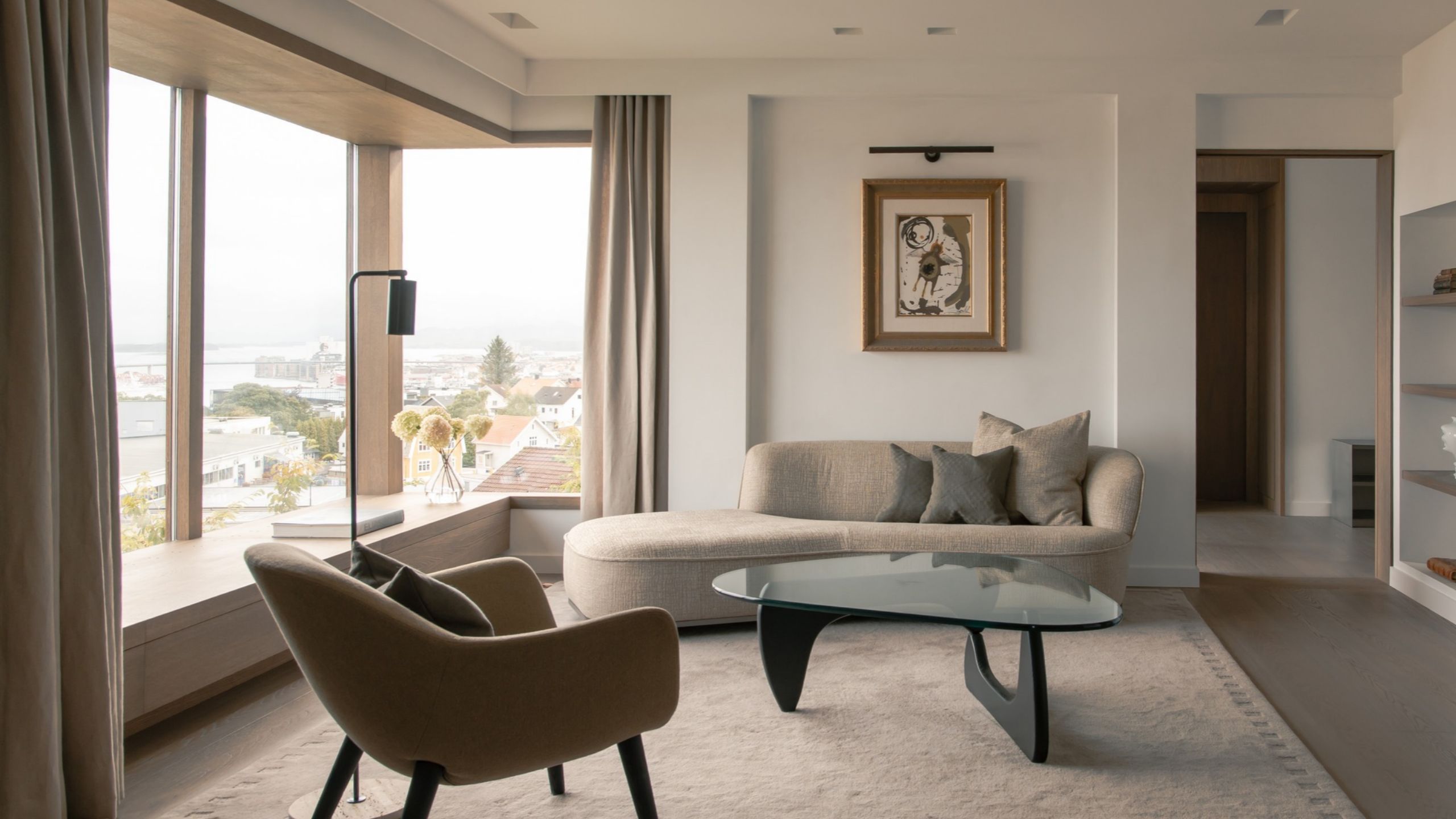 cozy living room with a day bed, a glass coffee table and a piece of art with an art light
