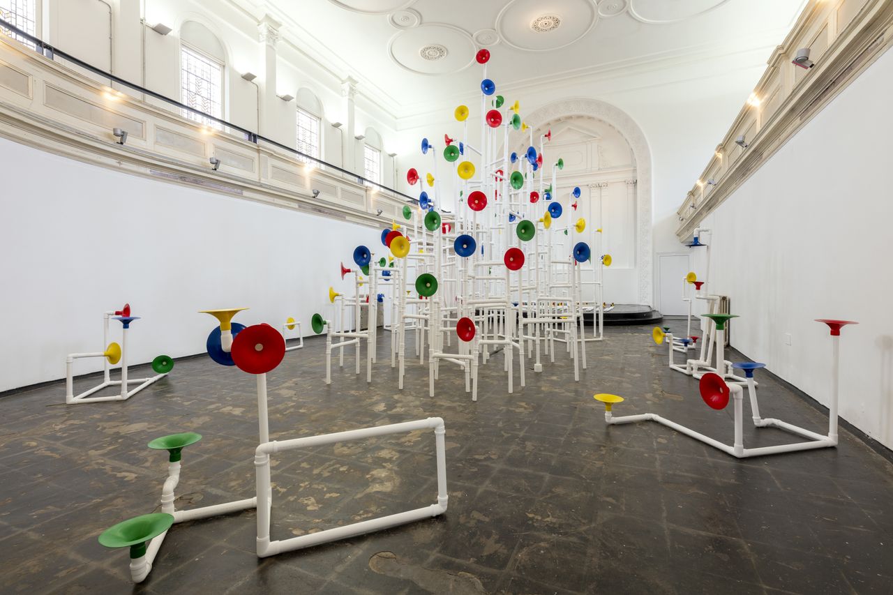 Installation in a former church made out of white pipes and colourful funnels