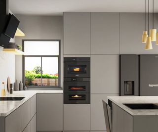 grey slab kitchen with built in ovens and which worktops
