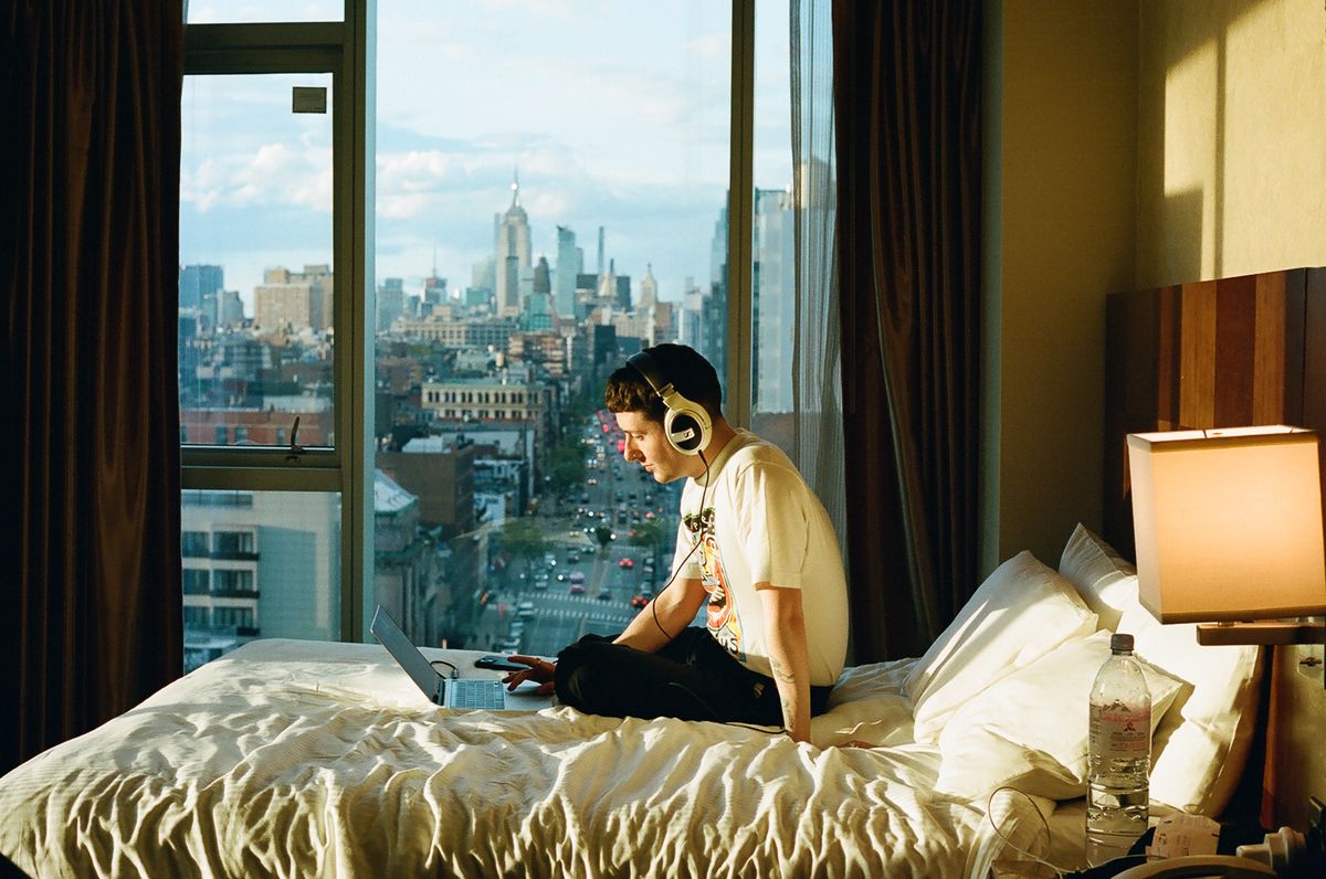 Scottish singer Joesef sits on his bed with a view in the background 