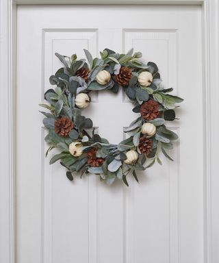Leaves and pinecone wreath on a white door