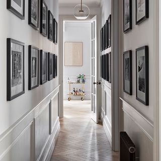 Light grey hallway with wooden floors and a gallery wall in black frames