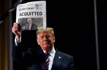 Trump holds a newspaper 