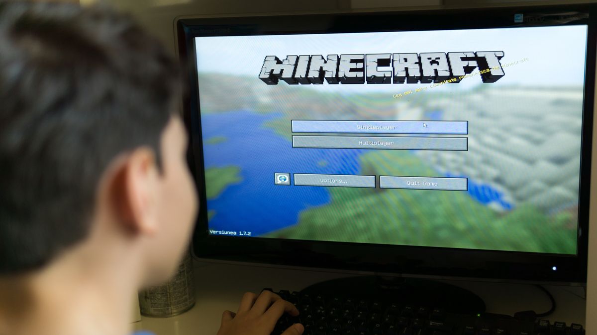 A boy playing Minecraft on a desktop PC