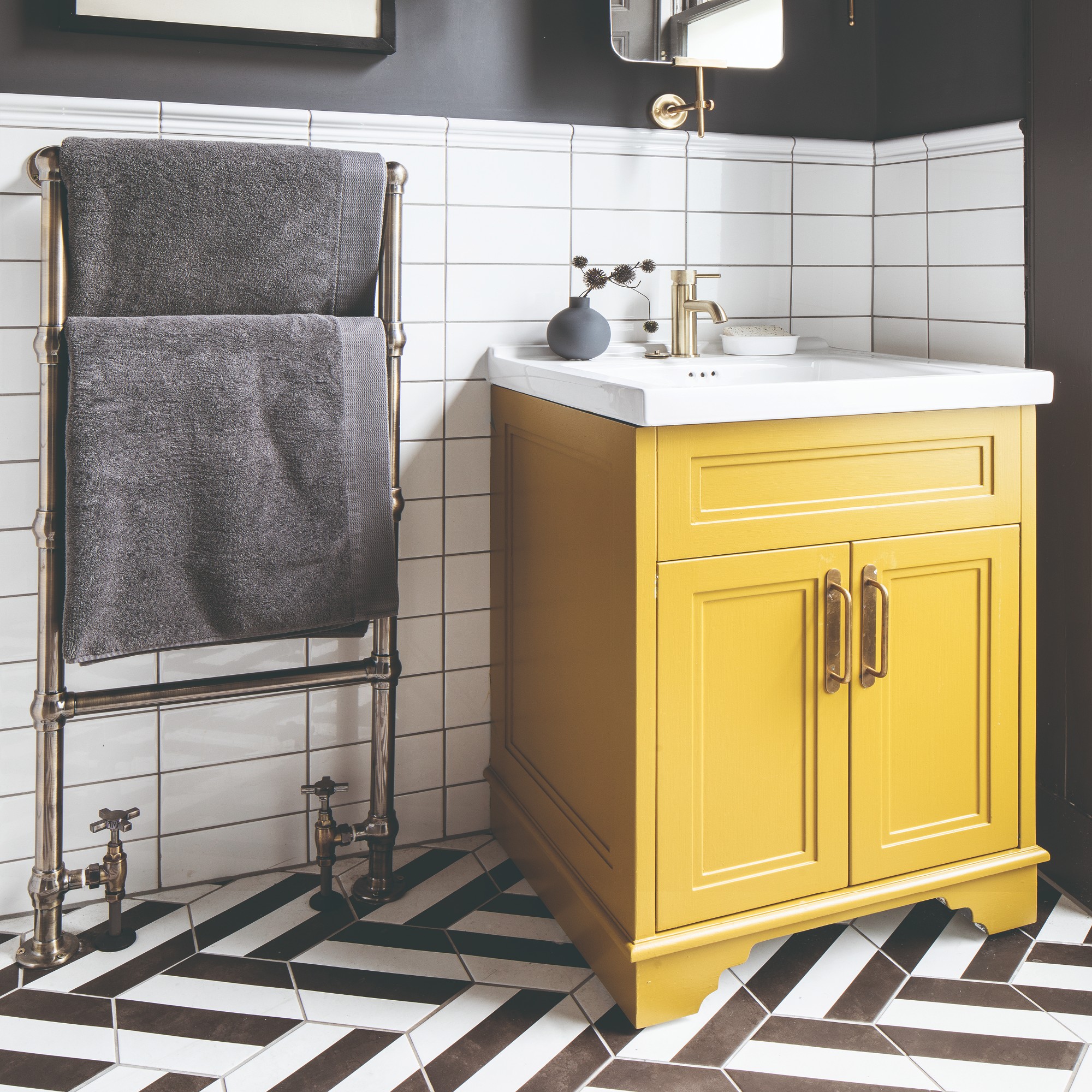 A tiled bathroom with a yellow sink cabinet