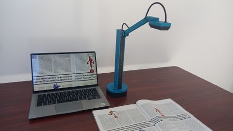Ipevo VZ-X document camera on desk scanning book and the image appearing on a laptop