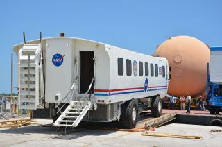 NASA's space shuttle crew transport vehicle (CTV), a modified airport "people mover," is loaded onto a barge at Kennedy Space Center for the Wings of Dreams Aviation Museum on April 24, 2013.