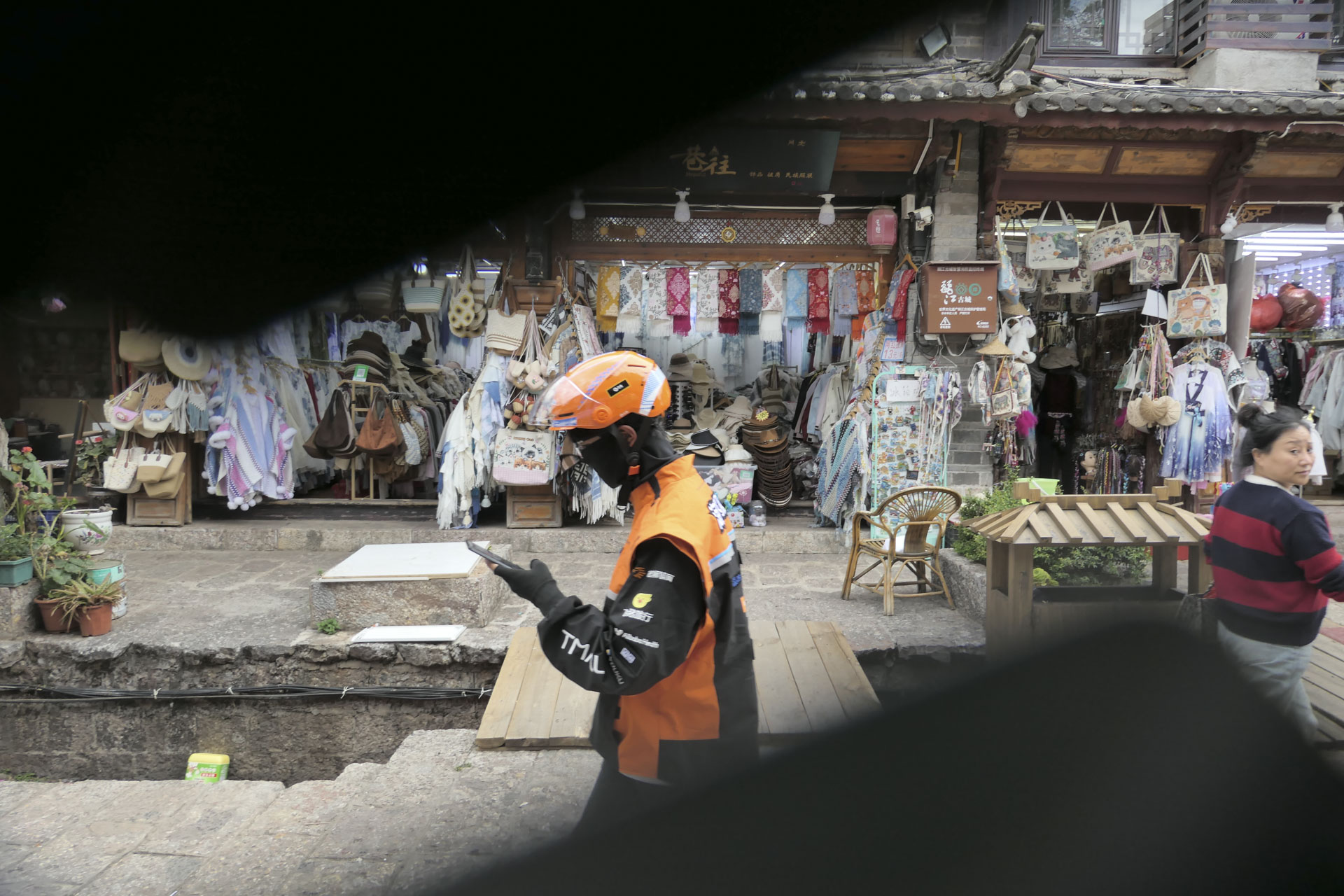 A street scene with a clothes shop and a driver walking past making a delivery