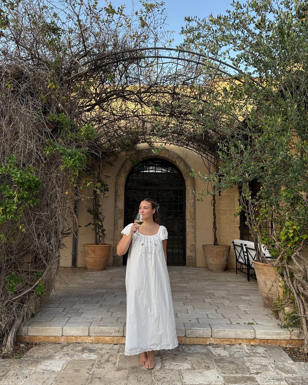@oliviamarcus, wears a white broderie anglaise dress