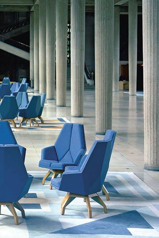 Blue chairs in a large room with stone pillars and a blue and cream tiled floor