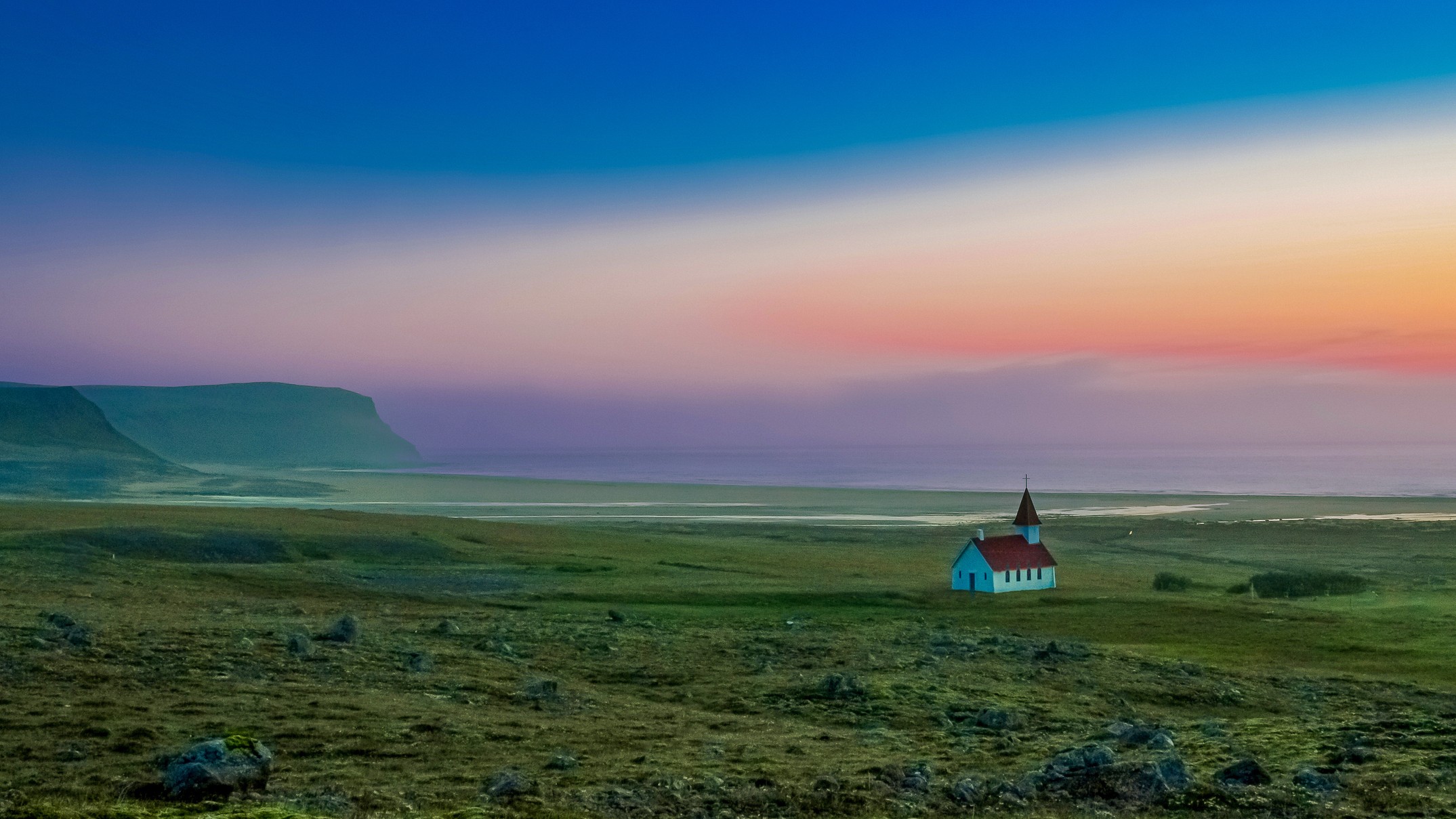 Dramatic Latrabjarg landscape with majestic Breidavik church standing alone by the beach under a golden sky with beautiful sunset colors in Breidavik, Latrabjarg, Westfjords, Iceland