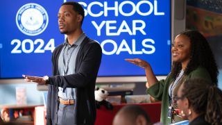 Gregory holding his hand out and Janine standing next to him, also holding up her hand.