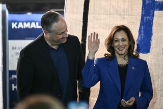 Vice President and Democratic presidential candidate Kamala Harris (R) waves to the audience alongside Second Gentleman Douglas Emhoff during a stop on their campaign bus tour in Rochester, Pennsylvania