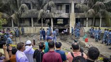 Onlookers gather as Bangladesh Air Force personnel inspect the crash site a day after a training jet crashed into a school in Dhaka