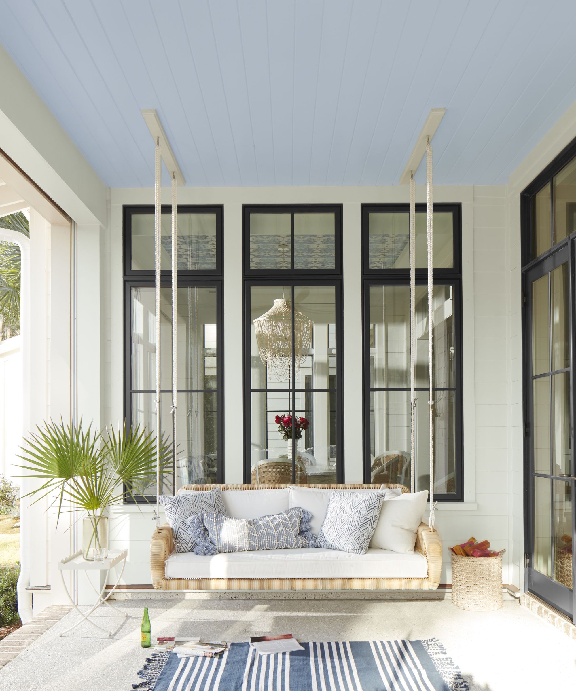 Swing seat in a porch with white painted wood and an outdoor rug