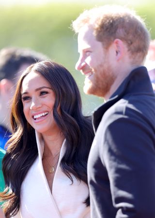 Prince Harry and Meghan Markle in profile smiling at the Invictus Games