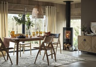 fall dining room with retro style furniture, log burner, rug, rattan lampshade, amber glassware, sideboard