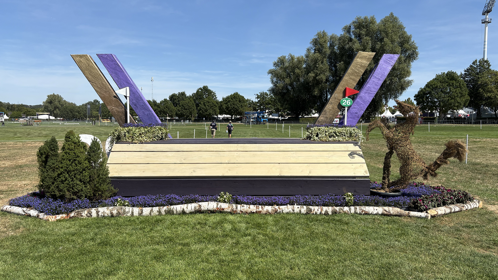 A table fence decorated with the purple and gold Aachen W on the eventing World Championships cross-country course
