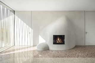 Terrazzo floor curves around a lime finish fireplace