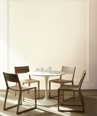 Cream colored wall with dining table and chairs