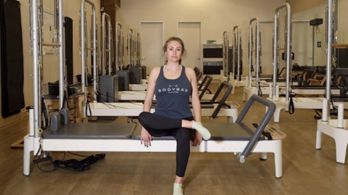 Woman on a Reformer Pilates machine demonstrating an exercise