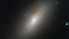 An image of NGC 4694, a smooth, glowing galaxy shaped like an ellipse with barely any star formation