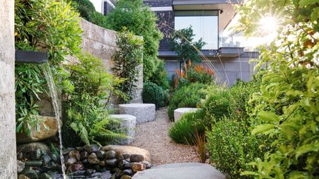 modern coastal garden with water feature, natural boulders, naturalistic planting and gravel path