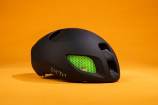 Smith Ignite helmet featured front side on in black with green inserts on an orange background