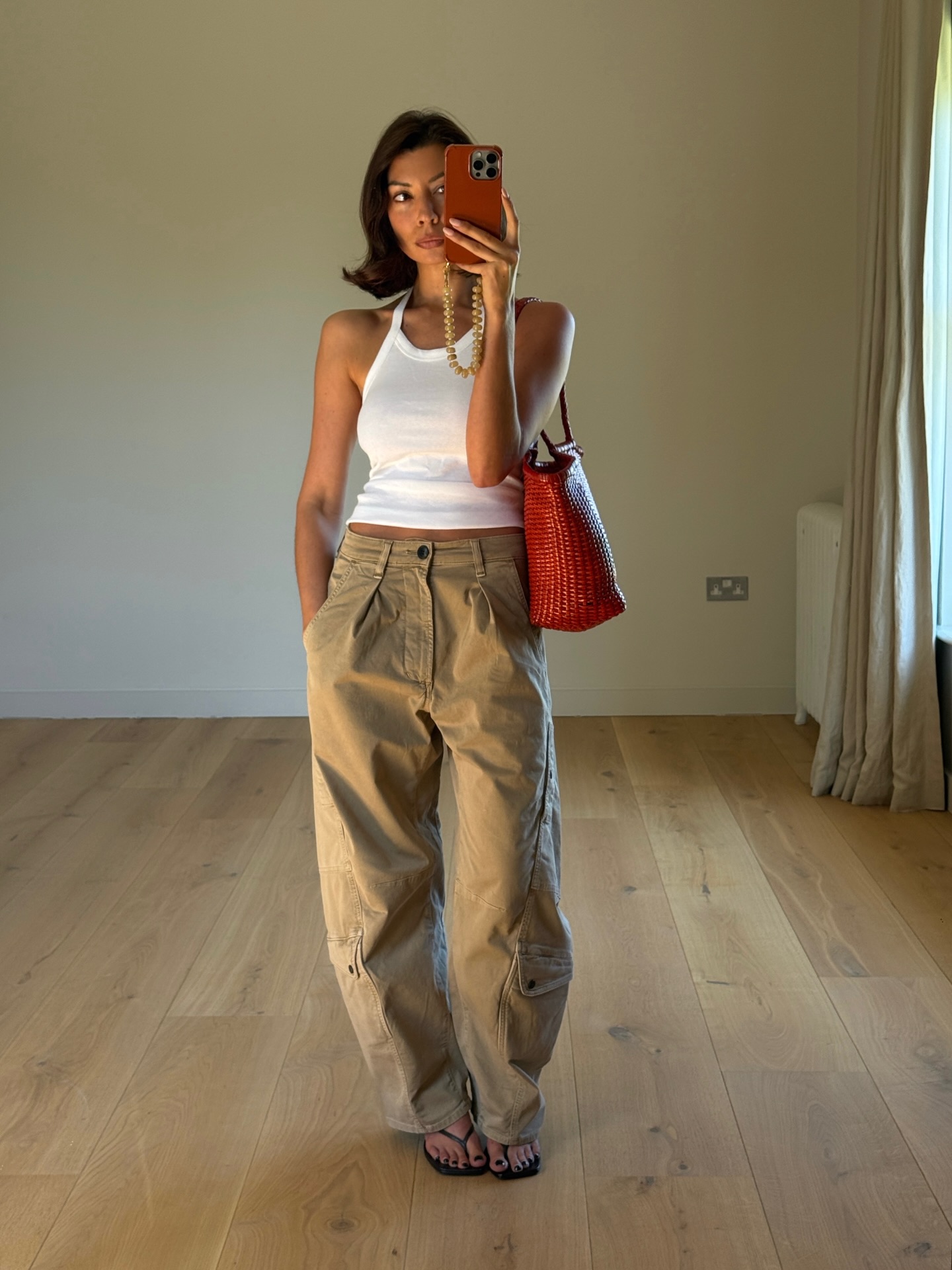 An image of @smythsisters wearing a white tank top with khaki jeans.