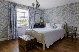bedroom with blue toile wallpaper, curtains and lightshades