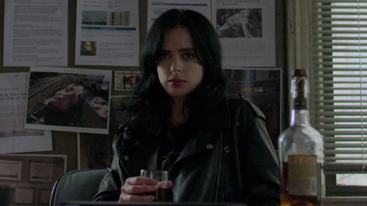 krysten ritter&#039;s jessica jones having a drink at her desk in netflix show