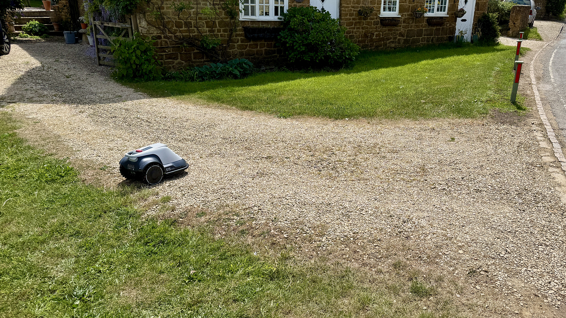 A robot lawn mower driving across a gravel pathway