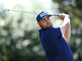 Dan Bradbury holding his finish position with an iron at the end of his golf swing