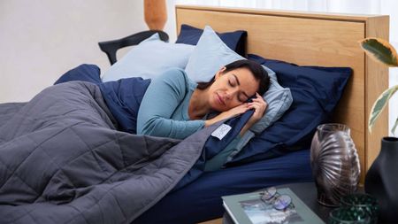 Woman sleeping in bed underneath a navy blue electric blanket