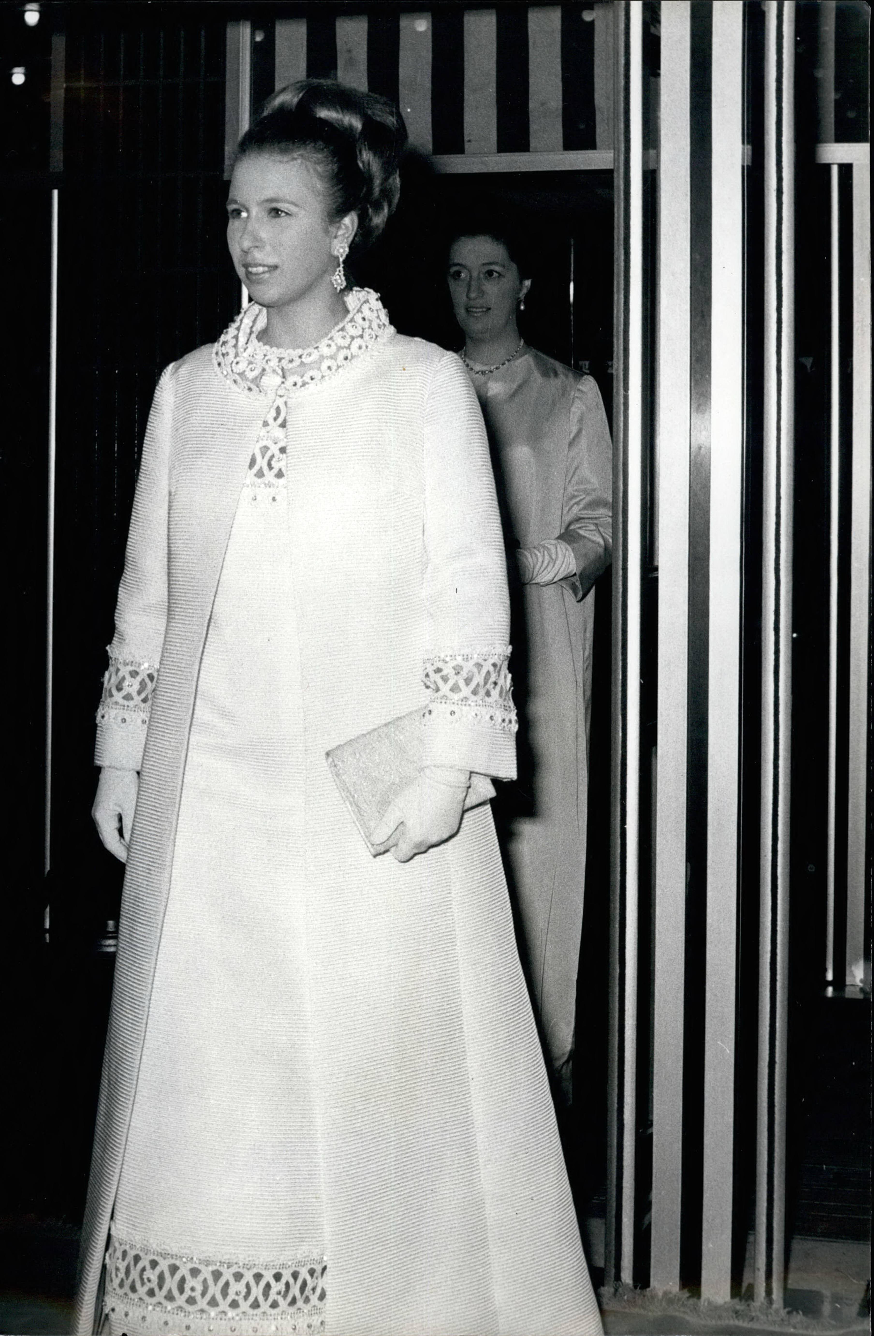 Princess Anne wearing a long white coat and dress walking through a doorway
