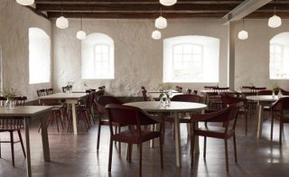 Wanås Hotel dining room with cream wooden table, brown chairs and rough plaster walls, exposed timber beams