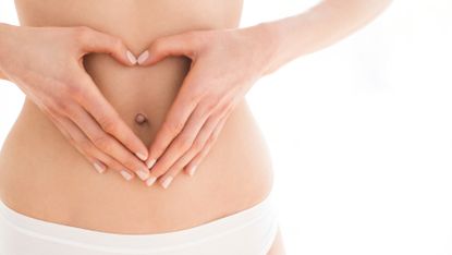 Woman creates a love heart with her hands over her stomach