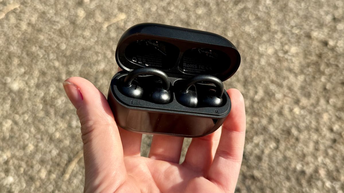 Someone holding the Tozo OpenEarRing buds in a charging case