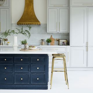 White kitchen with dark blue island and bronze cooker hood