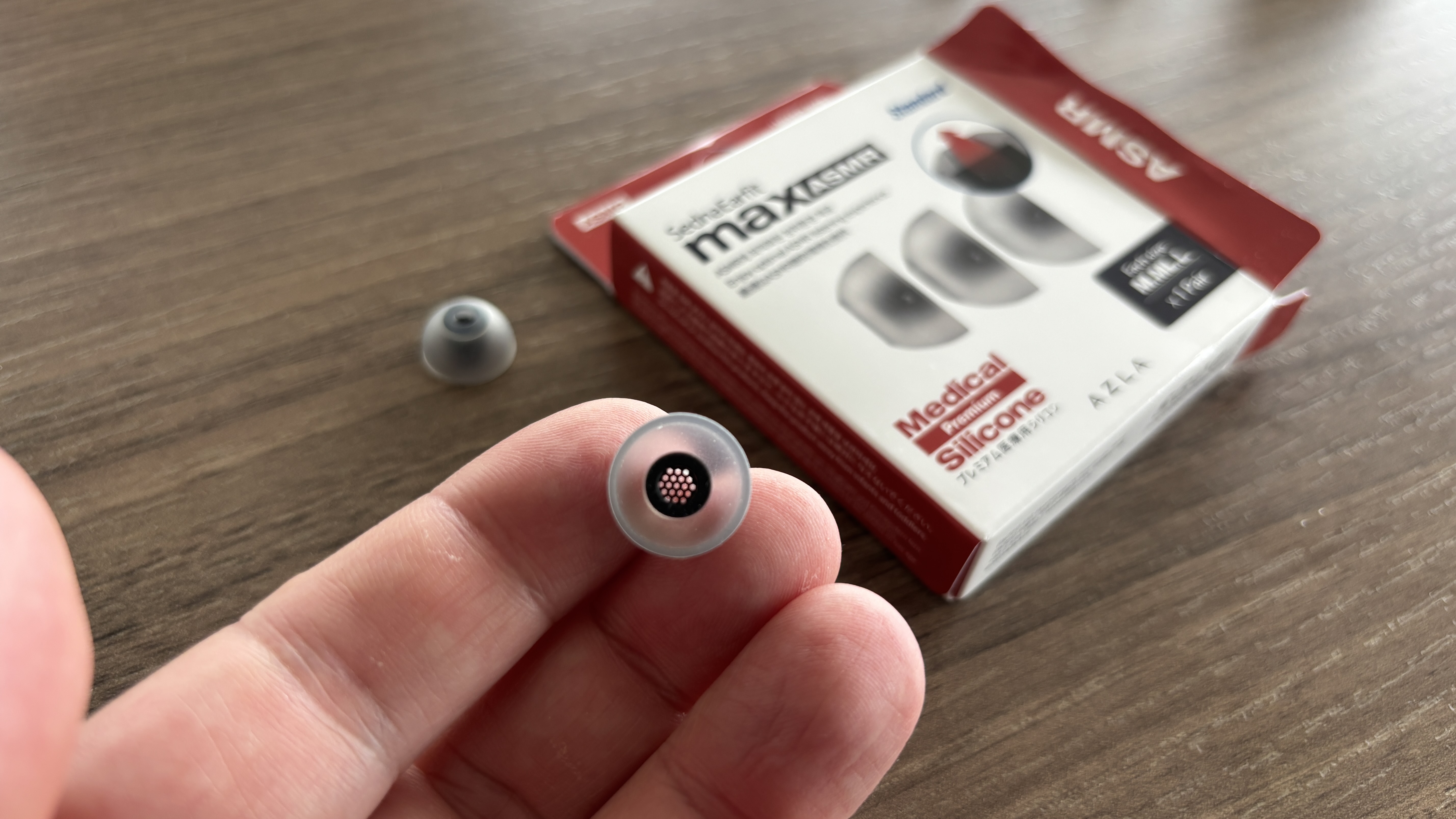 AZLA SednaEarfit Max eartips being held in a hand next to their packaging