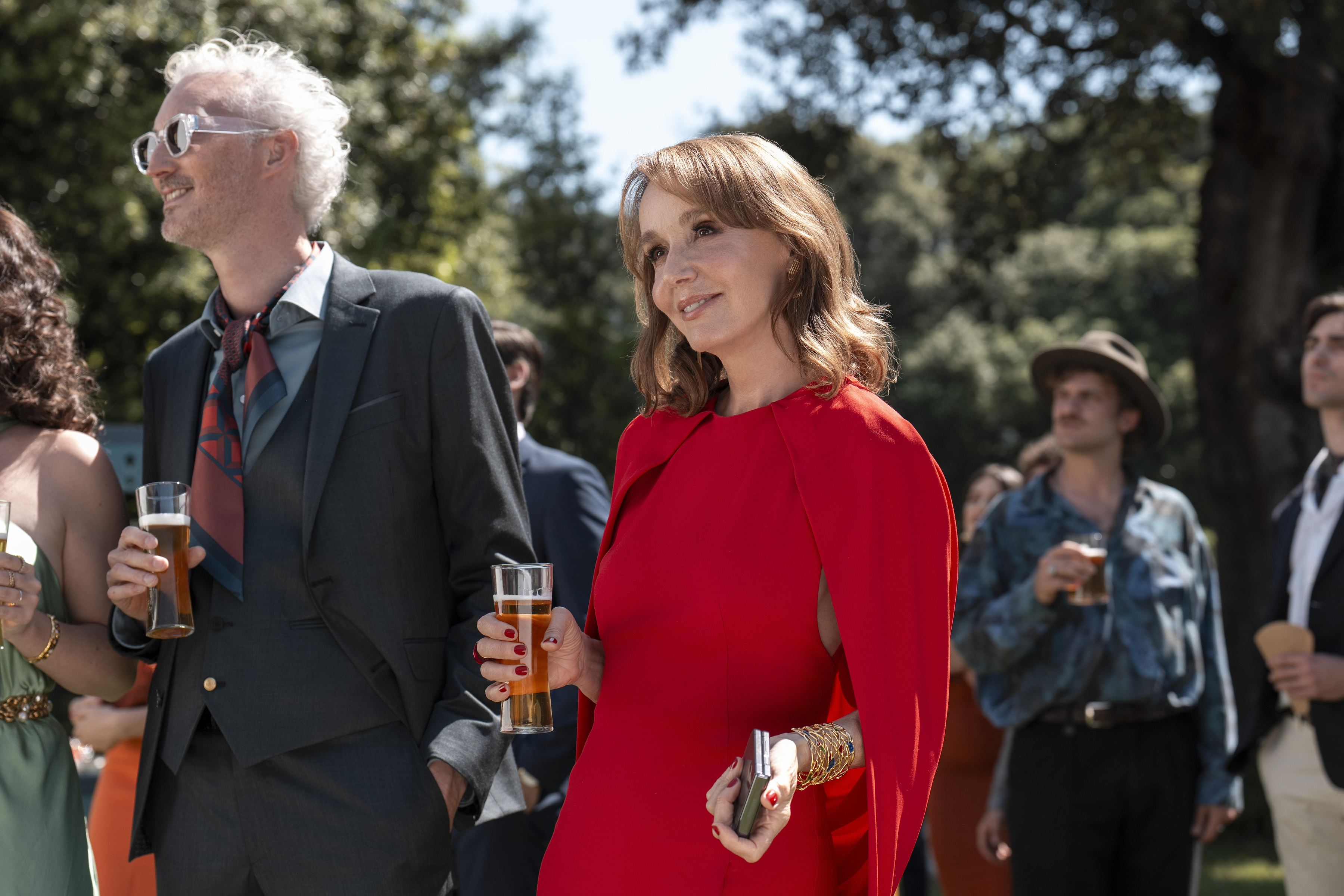 sylvie wears a red dress at a garden party in emily in paris season 5