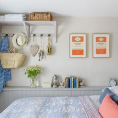 Small bedroom with grey wood panelling and bed with white, blue and orange bedding.