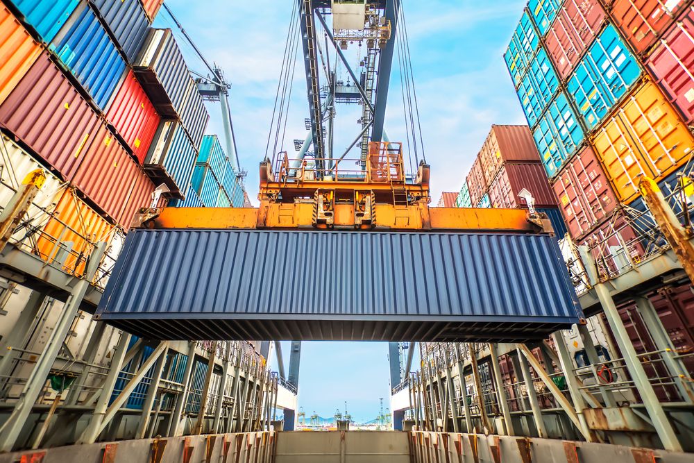 Crane lifting shipping container, surrounded by lots of shipping containers