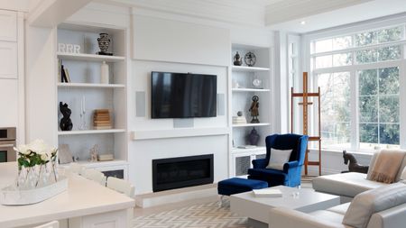 Luxury living room diner with deep blue armchair, mounted tv and tidy shelves