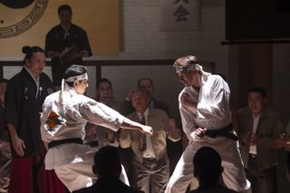 Ralph Macchio as Daniel LaRusso, fighting an opponent in a crowded gym, in 'Cobra Kai.'