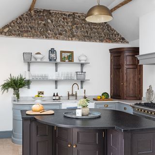 kitchen with dark island wooden panty and exposed stonework